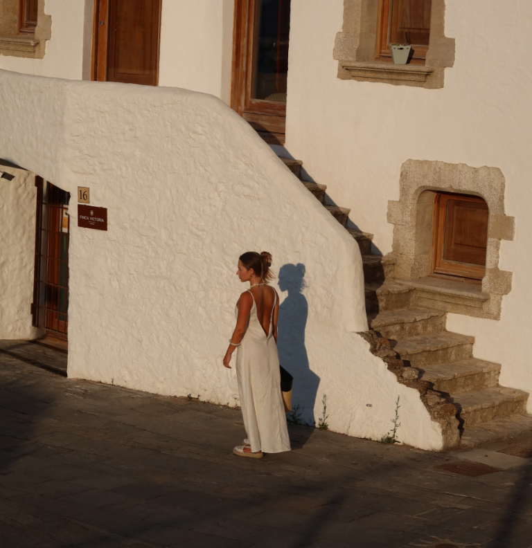 femme en robe blanche se baladant dans une rue et maisons blanches